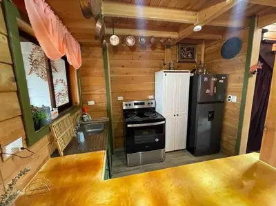 a kitchen with a stove and a refrigerator at Parque Nacional Volcán Poás Cabaña Abby in Bajos Tigre