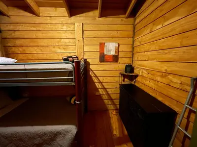 a small room with a bed in a wooden cabin at Parque Nacional Volcán Poás Cabaña Abby in Bajos Tigre