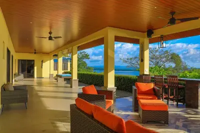 a porch with orange chairs and a view of the ocean at Ojochal Magnificent Ocean View in Ojochal