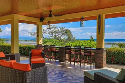 a patio with chairs and tables and a view of the ocean at Ojochal Magnificent Ocean View in Ojochal