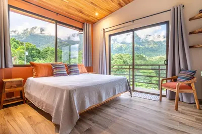 a bedroom with a bed and a large window at Villa Roca Ocean to Mountain Views - by Pura Villas in Ojochal