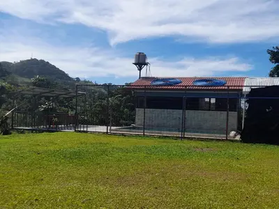 a building with a fence next to a grass field at Casa árbol in Aguas Zarcas