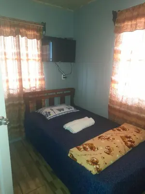 a bedroom with two beds and a television and windows at Casa árbol in Aguas Zarcas