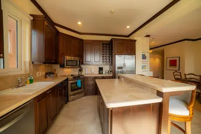 a large kitchen with wooden cabinets and a counter top at AltaVista 2C 3 bdr Ocean View in Los Suenos in Herradura