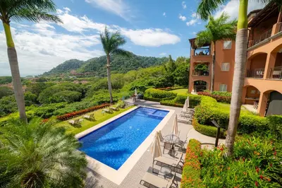 an exterior view of a house with a swimming pool and palm trees at AltaVista 2C 3 bdr Ocean View in Los Suenos in Herradura