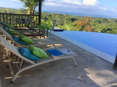 a pool with chaise lounge chairs next to a swimming pool at PRIVATE SPACE Just you and the Birds with PRIVATE INFINITY POOL in Uvita