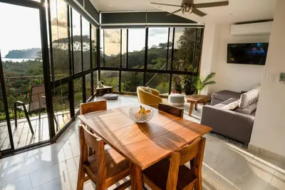 a living room with a wooden table and a large window at Modern condo with stunning ocean views in Samara in Sámara