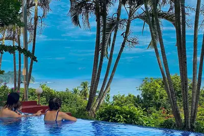 two women in a swimming pool with palm trees at Modern condo with stunning ocean views in Samara in Sámara