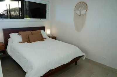 a bedroom with a bed with white sheets and a window at Modern condo with stunning ocean views in Samara in Sámara