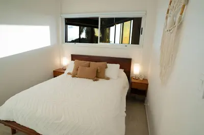 a bedroom with a white bed with a window at Modern condo with stunning ocean views in Samara in Sámara