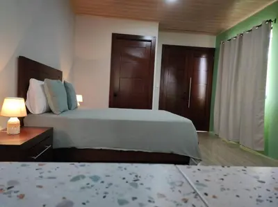 a bedroom with a bed and a nightstand with a lamp at Mandy Loft -40MB wifi -8 miles from La Fortuna in San Ramón