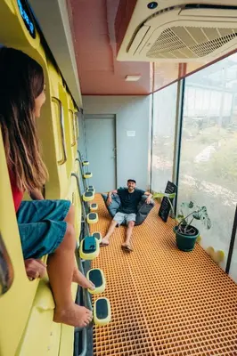 a man sitting on a train looking out the window at Capsule Pupa House in Tamarindo