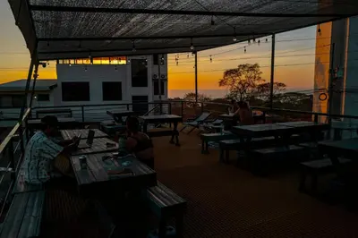a group of people sitting at tables on a balcony at Capsule Pupa House in Tamarindo