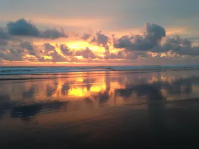 a sunset on the beach with a reflection in the water at Rafiki Beach Camp in Matapalo