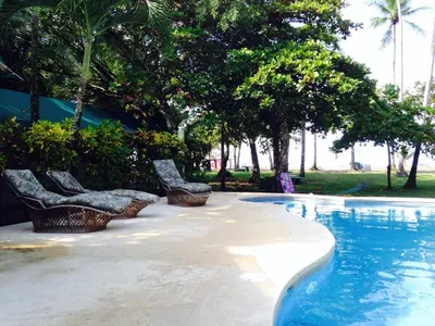 a swimming pool with benches and trees in a park at Rafiki Beach Camp in Matapalo
