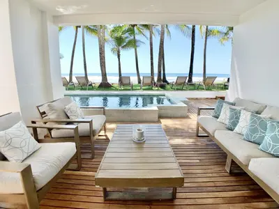 a living room with a pool and palm trees at Modern Beachfront Paradise - Hermosa Palms 8 in Playa Hermosa