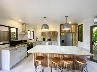 a kitchen with a large island with bar stools at Villa Arenas- Private Pool & Easy Beach Access in Jaco in Jacó