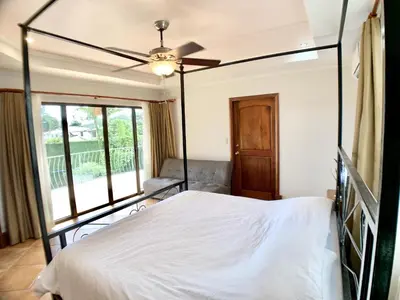 a bedroom with a white bed with a ceiling fan at Villa Arenas- Private Pool & Easy Beach Access in Jaco in Jacó