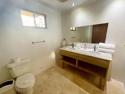 a bathroom with a sink and a toilet and a mirror at Villa Arenas- Private Pool & Easy Beach Access in Jaco in Jacó