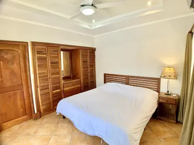 a bedroom with a white bed and wooden cabinets at Villa Arenas- Private Pool & Easy Beach Access in Jaco in Jacó