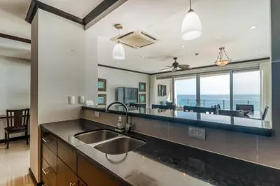 a kitchen with a sink and a large window at Elegant Beachfront Condo at Diamonte del Sol - 801s in Jacó
