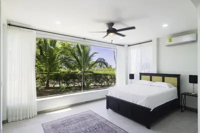 a bedroom with a bed and a large window at Classy Beachfront Home with Private Pool - Hermosa Palms 110 in Playa Hermosa