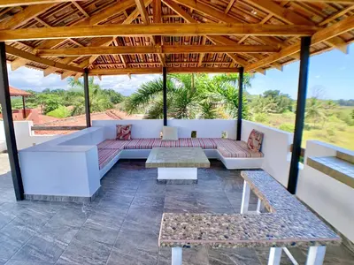 a covered patio with a couch and tables at Classy Beachfront Home with Private Pool - Hermosa Palms 110 in Playa Hermosa