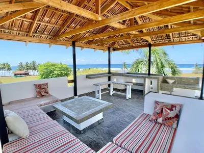 a patio with a table and benches and the ocean at Classy Beachfront Home with Private Pool - Hermosa Palms 110 in Playa Hermosa