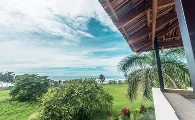 a view from the balcony of a house with a palm tree at Classy Beachfront Home with Private Pool - Hermosa Palms 110 in Playa Hermosa