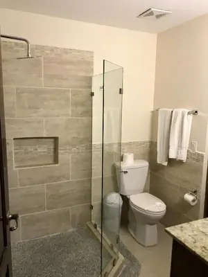 a bathroom with a toilet and a glass shower at Casa Suenos- Iconic 4BR Home with Private Pool in Jacó