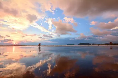 a person standing on a beach with a cloudy sky at Casa Suenos- Iconic 4BR Home with Private Pool in Jacó