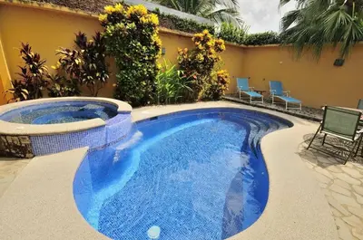 a swimming pool in a yard with chairs next to a house at Casa Suenos- Iconic 4BR Home with Private Pool in Jacó