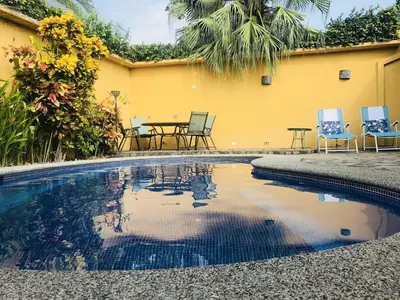 a pool with chairs and a table next to a house at Casa Suenos- Iconic 4BR Home with Private Pool in Jacó