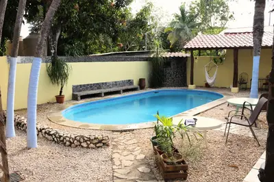 a swimming pool with a bench next to a house at Coconut Beach House in Playa Conchal