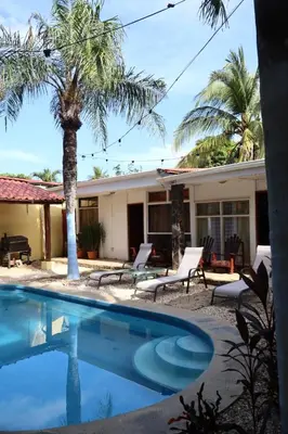 a house with a palm tree and a swimming pool at Coconut Beach House in Playa Conchal