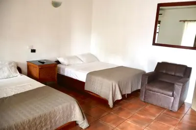 a room with two beds and a chair and a mirror at Coconut Beach House in Playa Conchal