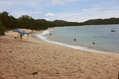 a group of people swimming in the water on a beach at Coconut Beach House in Playa Conchal
