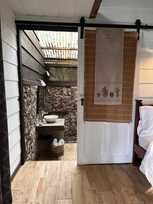 a door leading to a bathroom with a stone wall at Jicote finca de ecoturismo 2 in Cartago