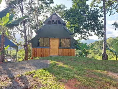 a small house with a black roof on a hill at Finca Makambu in Platanillo
