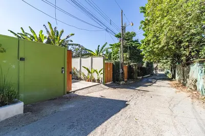 an empty street with a green fence and trees at Casa Bonimus in Santa Teresa Beach