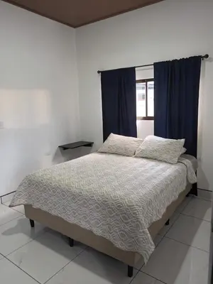 a bedroom with a bed with a blue curtain at Apartamento Rodriguez in Quepos