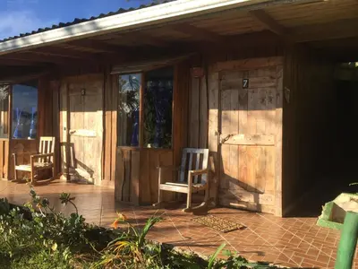 a porch of a wooden house with two chairs at Mirador Valle del General in La Ese
