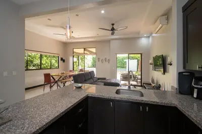 a kitchen with a counter top and a living room at Casa Aqua in Tamarindo