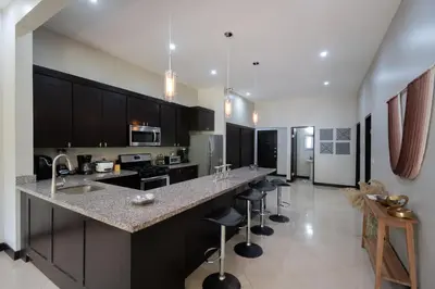 a kitchen with black cabinets and a counter with bar stools at Casa Aqua in Tamarindo