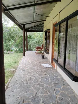 a porch of a house with awning and a bench at Natural paradise in Turrialba