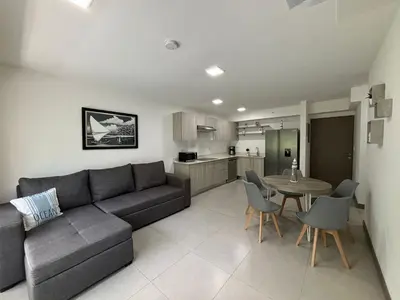 a living room with a couch and a table and a kitchen at Punta Esmeralda by Punta Leona in Jacó
