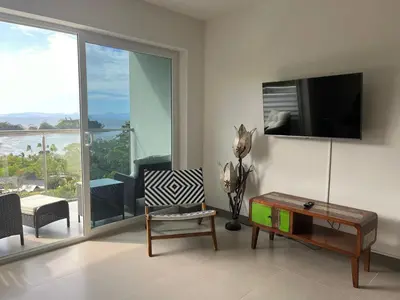 a living room with a tv and a chair and a table at Punta Esmeralda by Punta Leona in Jacó