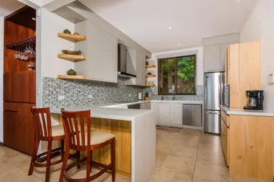 a kitchen with a counter with two chairs and a refrigerator at Casa Del Mar- 3 Br Ocean View House In Flamingo in Playa Flamingo