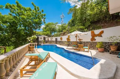 an outdoor swimming pool with chairs and an umbrella at Casa Del Mar- 3 Br Ocean View House In Flamingo in Playa Flamingo