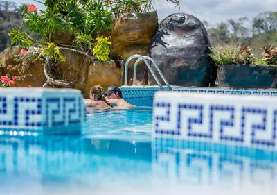 a man taking a picture of two people in a swimming pool at Hotel Le Priss in Manuel Antonio